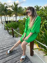 Vestido corto verde manzana de lino, con escote en V con volados y mangas abullonadas.