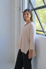 Sweater de punto color crudo, con escote en V, manga larga y diseño holgado con costura central vertical.
