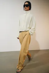 Chaqueta de nylon color crudo, con cuello alto, mangas largas, bolsillos delanteros, bajo abullonado con elástico y cierre frontal con botones forrados.