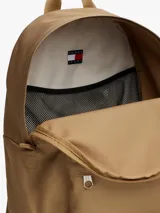 Mochila de diseño redondeado color beige, con compartimento principal y bolsillo frontal con cierre. Incluye parche con logo de la marca en la parte inferior, asa superior y correas acolchadas ajustables.