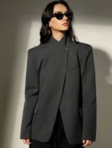 Blazer sastrero de corte oversized en color gris oscuro, con hombros estructurados, cuello mao y cierre frontal cruzado con un botón. Presenta bolsillos laterales con solapa y un bolsillo superior en el pecho.