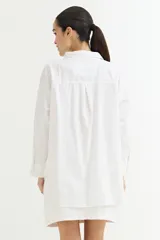 Camisa color crudo, de corte clásico, con cuello camisero, cierre frontal con botones y mangas 3/4 con trabillas.