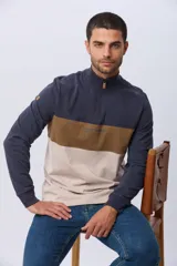 Remera polo de manga larga con diseño de bloques de color en azul marino, marrón y beige. Presenta cuello alto con cierre frontal parcial y estampa frontal con el logo de la marca.