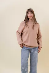 Sweater tejido de punto color blanco, con cuello alto y diseño en relieve tipo chevron en la parte frontal. Presenta un calce holgado con terminaciones acanaladas en puños y ruedo.