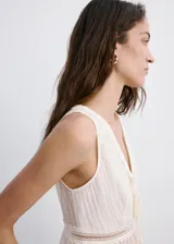 Top blanco sin mangas, con escote en V pronunciado, detalles de encaje y lazos ajustables en el frente. Presenta diseño corto y ligero con dobladillo con vuelo.