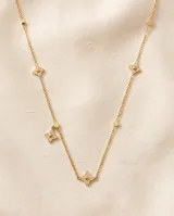 Collar de cadena fina con baño de oro, adornado con pequeños dijes en forma de estrella de cuatro puntas con incrustaciones de circonias.