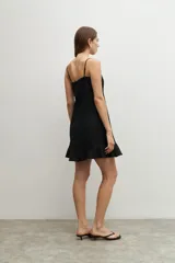 Vestido corto blanco de lino con breteles finos, corte recto y volado en el ruedo.