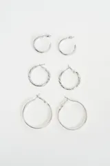 Set de tres pares de aros tipo argolla en color plateado, con diferentes texturas y tamaños, incluyendo un par liso pequeño, un par con textura trenzada mediano y un par liso grande.