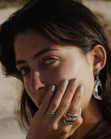 Par de aros colgantes de bronce y alpaca color plateado, con forma orgánica irregular y textura martillada. Cierre con perno y mariposa de plata 925.