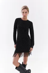 Vestido corto de algodón y lúrex color negro con hilo metálico, manga larga, cuello redondo y detalle de flecos en el ruedo.