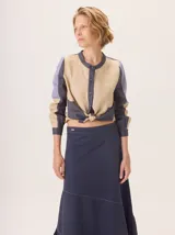 Camisa de algodón con diseño color block en tonos beige, azul marino y lila. Presenta cuello redondo, cierre frontal de botones y mangas largas. El bajo de la camisa está anudado al frente.