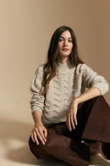 Sweater de punto color beige con diseño geométrico en relieve, cuello alto y mangas largas con puños acanalados.
