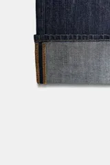 Pantalón de jean de tiro medio con corte recto y cinco bolsillos. Presenta un acabado con dobladillo ancho en el bajo y cierre frontal con botones metálicos.