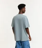 Remera de corte relaxed, confeccionada en algodón de tejido grueso con cuello redondo y mangas cortas.