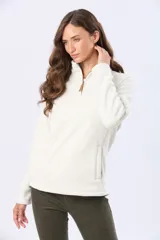 Buzo de polar color crema con cuello alto y cierre frontal parcial. Presenta detalles en cuero en el tirador del cierre y un pequeño bordado en el pecho y en la manga.
