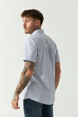 Camisa de manga corta con estampado de cuadros vichy en azul y blanco. Presenta cuello con botones, cierre frontal con botones y logo bordado en el pecho.