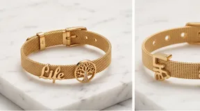 Pulsera de acero italiano con baño de oro, diseño de malla metálica con dijes colgantes del Árbol de la Vida y la palabra 'life', decorada con barras de circonias.