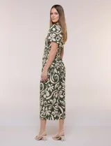 Enterito verde oscuro con estampado floral y abstracto en tono beige, de corte suelto y caída fluida. Presenta escote en V, mangas cortas, cintura elastizada con faja fruncida y pantalón crop de pierna ancha con bolsillos laterales.