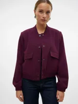 Campera bomber corta de color beige, confeccionada en tejido sarga, con cuello tipo rib, cierre frontal de botones a presión, bolsillos frontales con solapa y puños y dobladillo elasticados.
