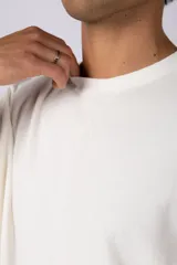 Remera de corte oversized en color marrón, confeccionada en tejido de algodón con textura de micropanal. Presenta cuello redondo con detalle de costura en forma de X y mangas cortas de estilo caído.