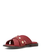 Sandalias planas de cuero rojo con tiras cruzadas y tachas metálicas doradas.