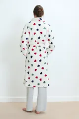 Bata de estar por casa confeccionada en tejido de poliéster suave, con diseño estampado de corazones en colores rojo, negro y verde sobre fondo blanco. Presenta un corte holgado, mangas largas y bolsillos frontales.