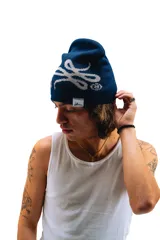 Gorro de lana tejido reversible, un lado azul marino y el otro gris, con diseño de moños en ambos lados.