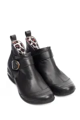 Botin de cuero negro con suela de goma tipo burbuja, diseño clásico con hebilla metálica lateral y elásticos para mayor ajuste.