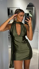 Vestido corto de satén color verde oliva, con escote halter y diseño cruzado en el cuello. Presenta una caída fluida y un corte ajustado al cuerpo.