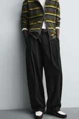 Pantalón de corte balloon fit en color gris, confeccionado en tejido con viscosa. Presenta pliegues frontales, cintura con cinturón integrado a contraste, bolsillos laterales y bolsillos traseros de vivo.