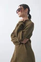 Vestido corto de punto en color beige, con cuello alto acanalado, mangas largas con puños ajustados y diseño holgado.