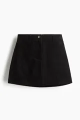 Pollera mini evasé color negro de pana, con cierre y botón frontal, y trabillas para cinturón.