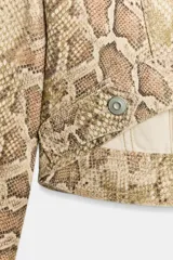 Cazadora de cuello solapa y manga larga con estampado animal print de serpiente, bolsillos con solapa en el pecho y cierre frontal con botones metálicos.