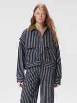 Campera de denim a rayas verticales con cuello de pana en color bordó. Presenta cierre frontal, mangas desmontables con cierre en los hombros, canesú en el pecho y bolsillos de parche cuadrados.