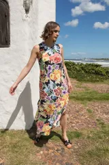 Vestido midi sin mangas con corte recto y tajos laterales en el ruedo. Presenta un estampado floral multicolor sobre base negra y cierre con botón en la espalda.