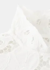 Blusa de encaje blanco con diseño floral, cuello alto y mangas largas con hombreras. Presenta un corte ajustado y acabado delicado.