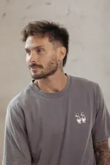Remera color durazno de corte recto y manga corta, con cuello redondo y pequeño bordado de dos patos en el pecho.