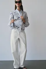 Jeans de mezclilla en color negro gastado, tiro bajo, corte de pernera recta y diseño clásico de cinco bolsillos con cierre frontal de cremallera y botón metálico.