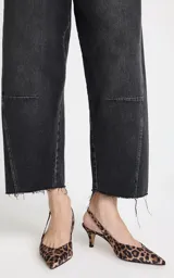 Jean de tiro alto con corte ancho y pierna recta, confeccionado en denim de lavado oscuro. Presenta costuras horizontales en la parte frontal de las rodillas, bolsillos traseros, cierre frontal con cremallera y botón, y dobladillo deshilachado.