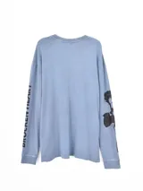 Remera de manga larga en color gris oscuro con efecto lavado. Presenta un estampado frontal con la frase 'LOVE IS HARDCORE' y un diseño gráfico de un corazón con ojos.