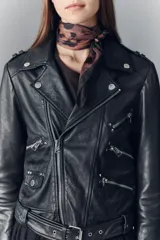 Campera estilo biker confeccionada en cuero ovino, con solapas amplias, charreteras en los hombros y múltiples cierres metálicos frontales. Presenta un diseño ajustado con detalles de herrajes plateados y forro interior de poliéster.