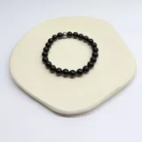Pulsera elástica con cuentas esféricas de ágata negra de 8mm y un separador de acero hipoalergénico. Contorno aproximado de 20 cm.