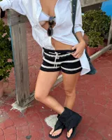 Botas negras de caña media, estilo sandalia-bota, con diseño tipo chinela en la parte delantera (dedo separado) y caña de tela suave y holgada. Presentan una tira ajustable con hebilla metálica plateada alrededor del tobillo.