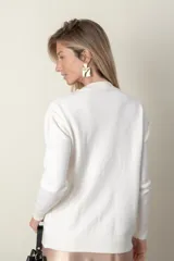 Sweater rojo de punto con cuello redondo, mangas largas, trenzado central y bolsillos delanteros.