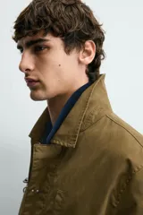 Parka de corte relajado confeccionada en mezcla de algodón color marrón. Presenta cuello solapa, cierre frontal con cremallera oculta y alamares metálicos, bolsillos de plastrón con solapa en la cadera y bolsillo de vivo en el pecho.