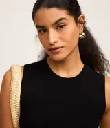 Blusa sin mangas color beige confeccionada en tejido de punto con textura acanalada y cuello redondo.