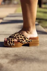 Sandalias de madera con plataforma y taco bajo, con tira ancha de cuero con estampado animal print y apliques de tachas plateadas.