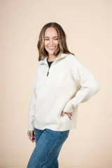 Cardigan de punto color crema, con cuello alto y cierre frontal parcial, de manga larga y diseño holgado.