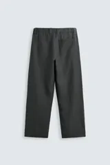 Pantalón de corte relajado confeccionado en tejido de cáñamo color blanco roto. Presenta cintura elástica con cordón interior ajustable, cierre frontal con botones, bolsillos laterales y un bolsillo trasero de plastrón.