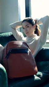 Mochila pequeña de símil cuero color negro, con bolsillo frontal con cierre, asa de mano y correas regulables.